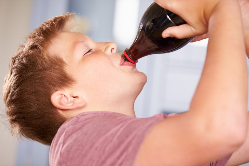 kind drinkt cola uit fles